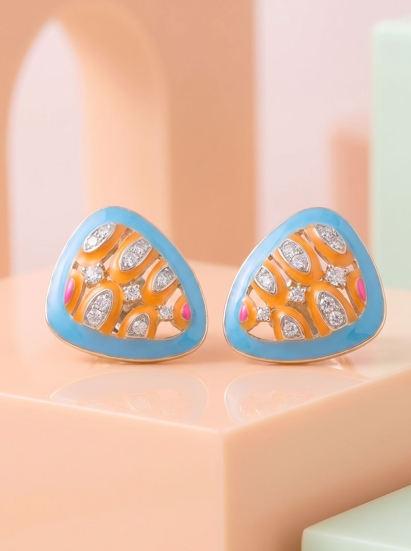 A contemporary pair of earrings inspired by vibrant coral reefs and sunlit ocean landscapes, featuring vivid cloisonné enamel in turquoise, coral orange, and fuchsia pink. Crafted in 925 silver with gold plating and accented with shimmering Swarovski crystals, they blend artistic colour with modern sophistication.