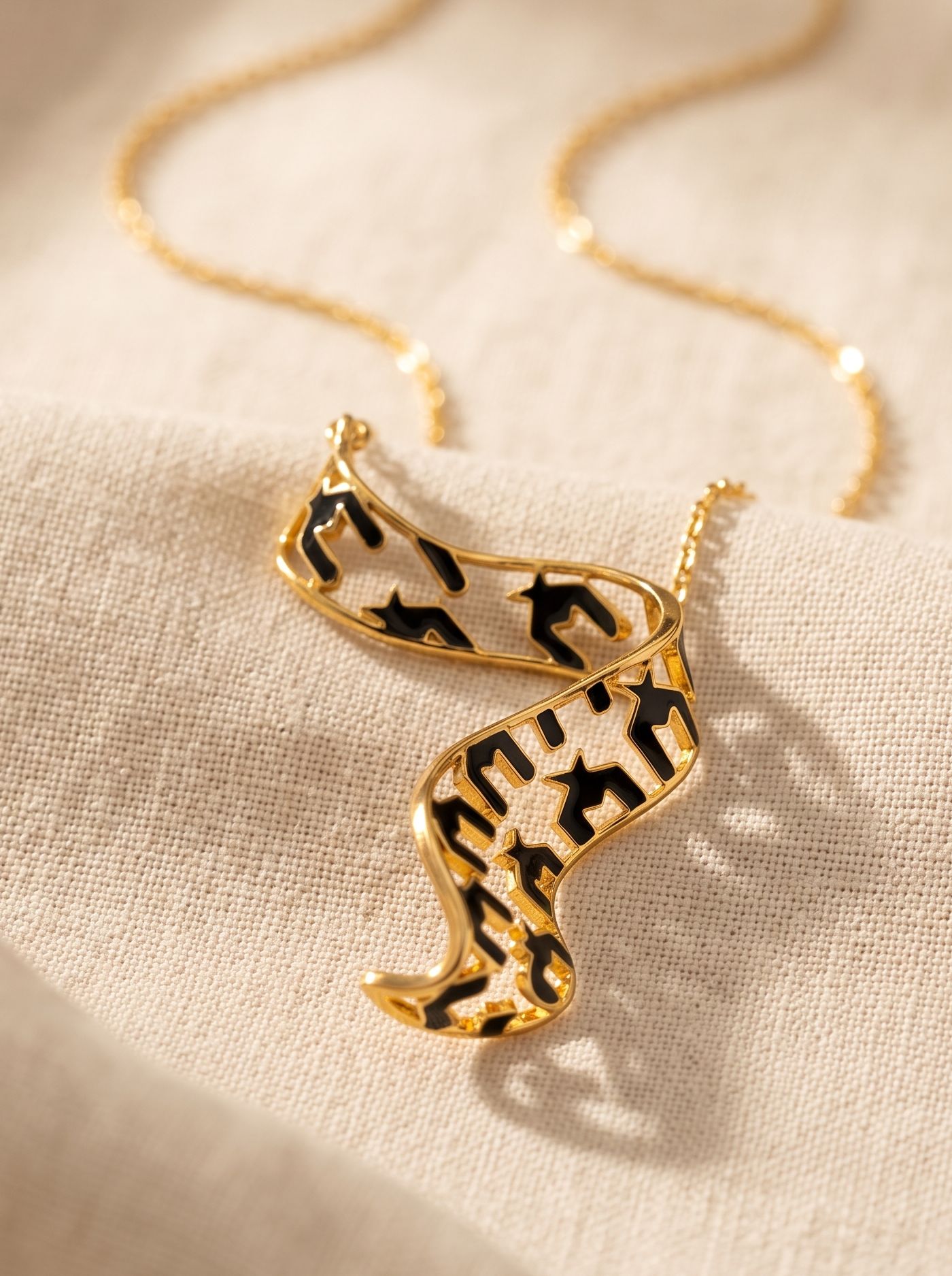 Crafted in 925 silver with gold plating, this pendant features cloisonné enamel in a contemporary design. Inspired by the effortless flow of ribbons, its sculptural form creates a graceful statement that is both artistic and timeless.