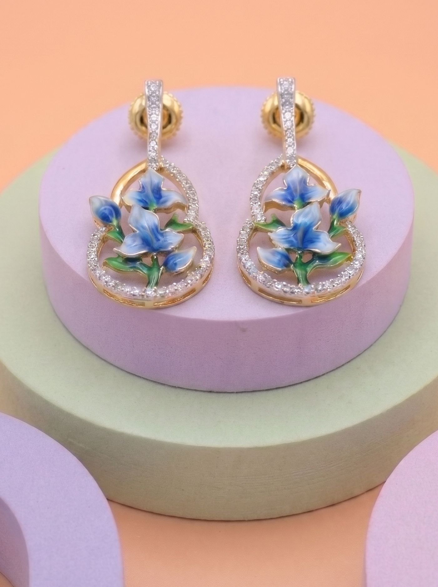 A contemporary pair of earrings inspired by delicate blue blossoms in bloom. Adorned with Swarovski crystals and hand-finished cloisonné enamel, these elegant earrings are crafted in 925 silver with gold plating, blending graceful florals with timeless sophistication.
