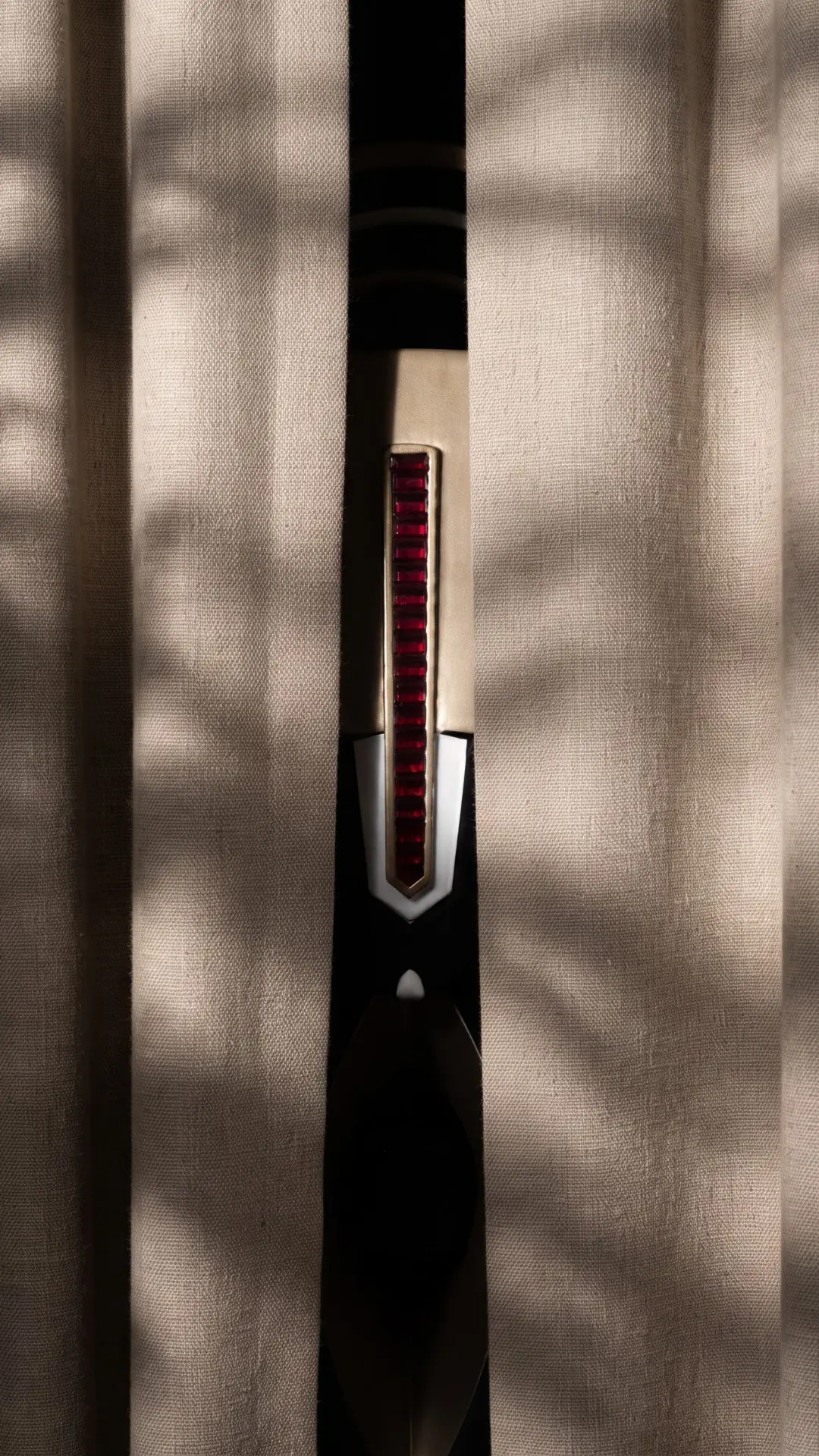 A gap between two linen curtains, a slice of the work lit behind them